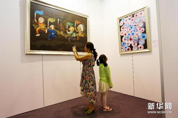 8月18日，观众观看印尼画家格雷斯·宗德罗内普瑙的作品《超越限制》（左）和美国画家维克多·安杰的作品《和谐》。