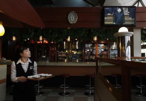 2012年4月11日，一家餐厅的服务员观看国家电视台对领导人金正恩参加党内会议的报道。