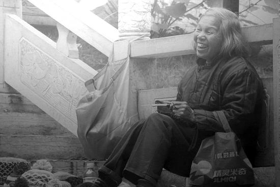 一位老妇人坐在桥边微笑(网页截图)