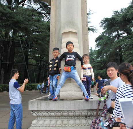 10月1日，江苏省南京市，有些家长为了拍照，让孩子爬上中山陵博爱牌坊基座。在全国大力宣传文明旅游的今天，南京中山陵景区仍然出现如此不文明现象。建华 摄