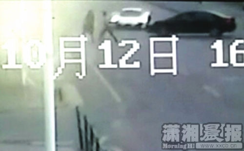 10月12日，车站北路，白色的迈凯伦跑车在撞上掉头黑色小车的同时又将两名横过马路的行人撞飞。监控视频截图