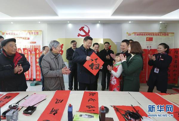 这是2月3日，习近平在南昌市东湖区彭家桥街道光明社区书画室，接过一位小朋友现场书写的 “福”字，祝大家都幸福。 新华社记者兰红光摄