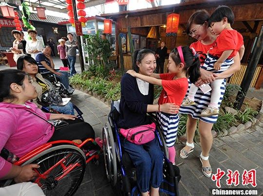 图为带着两个宝宝的妈妈与一位残疾女孩交流。 中新社记者 翟羽佳 摄