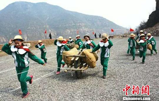 7月23日,一群学生在河南安阳红旗渠一起“推独轮车”，领略“后边来的要往前边放”推车、抬石精神，以期减压释放心灵。　何美芳　摄