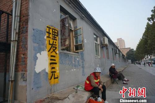 图为为使更多市民享受到实惠，侯春云在家属院门口做了一个“理发三元”的醒目标识。　王秋兰　摄