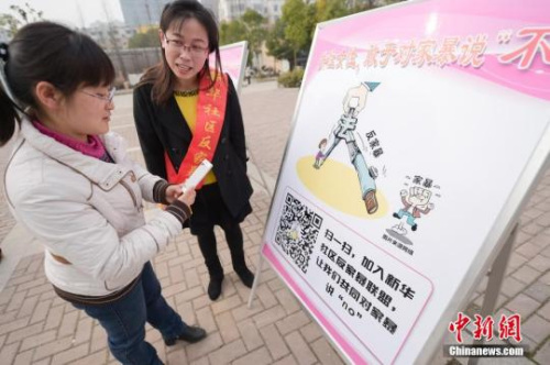资料图:2016年3月8日,安徽合肥新华社区志愿者夏一琼(右)向市民普及反家暴相关法律知识。钟欣 摄