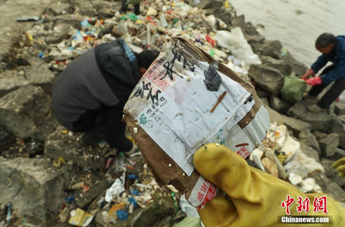 近日，上海崇明区东风西沙水库附近江面出现了大量来自外省市的生活垃圾。12月23日早间，中新网记者在上海崇明东风西沙水库岸边发现，这些垃圾正在被清理装袋，并伴有刺鼻气味。图为垃圾中来自外省市的快递包装随处可见。 张亨伟 摄