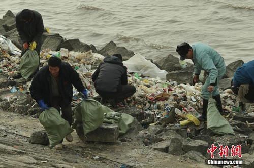 近日，上海崇明区东风西沙水库附近江面出现了大量来自外省市的生活垃圾。12月23日早间，中新网记者在上海崇明东风西沙水库岸边发现，这些垃圾正在被清理装袋，并伴有刺鼻气味。图为上海崇明区第一时间组织水务、环保、市容、海事、应急等部门开展应急处置相关工作。张亨伟 摄
