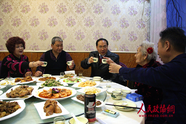 一家人共同举杯为老人拜年祝福。