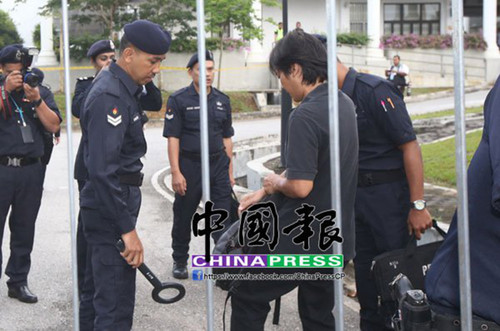 媒体在法庭大门外排队等待注册及进入庭内採访前，还需经防弹专家的检测。