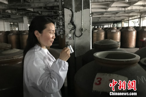 高玲在品尝装在酒缸里的原酒。<a target='_blank' href='http://www.chinanews.com/' >中新网</a> 种卿 摄