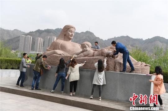 5月3日，来自兰州市市政工程管理处信息中心的志愿者顶着骄阳，反复用布擦拭着兰州地标建筑“黄河母亲”雕塑上的尘土。　杨艳敏 摄