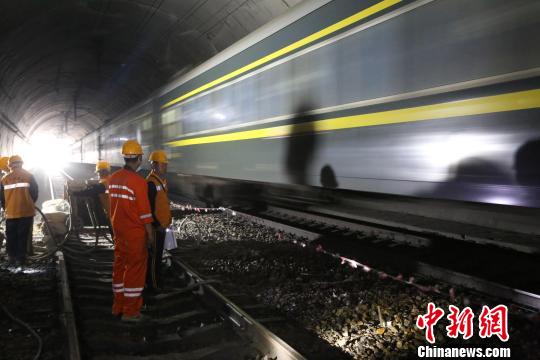 图为，飞驰的列车从施工人员身边擦身而过 杨乐 摄