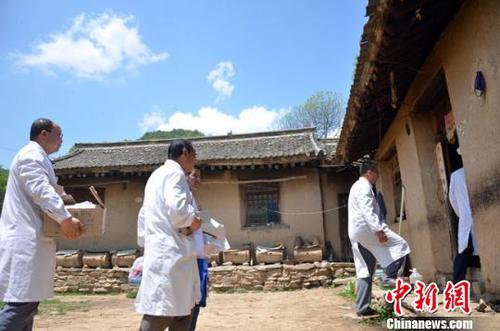 图为邹晓峰和医护人员在贫困农户的院子里。　冯志军 摄