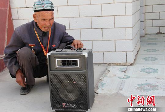 胡达拜地·依明老人正在用扩音设备播放国歌。　史玉江 摄