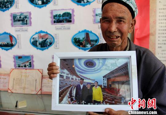 图为老人给<a target='_blank' href='http://www.chinanews.com/' >中新网</a>记者展示2012年10月1日随当地边防官兵去北京观看升国旗后，与老伴和孙女一起参观人民大会堂的照片。　史玉江 摄