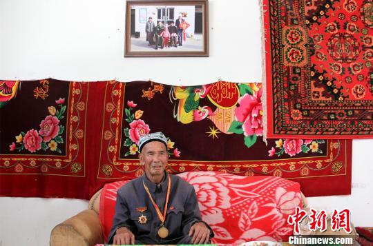 图为胡达拜地·依明老人在客厅里介绍自己做护边员时的经历。　史玉江 摄