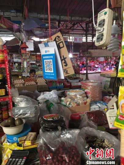 图为燎源菜市的干货摊位上方悬挂着收款二维码。　周潇男 摄