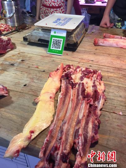 图为燎源菜市的牛肉摊位张贴着收款二维码。　周潇男 摄