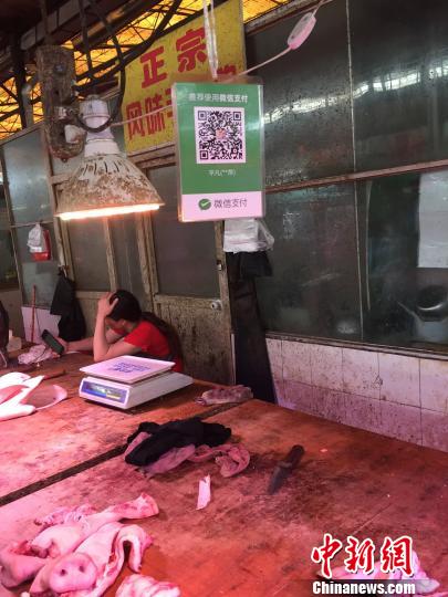 图为燎源菜市的猪肉摊位上方悬挂着收款二维码。　周潇男 摄