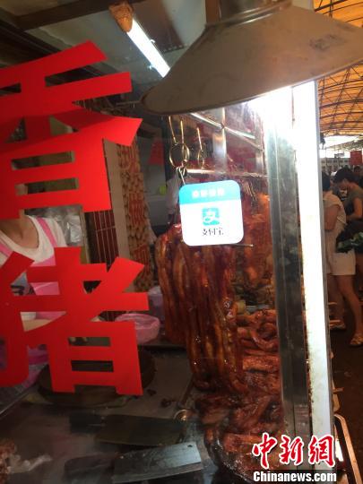 图为燎源菜市的熟食摊位上方悬挂着收款二维码。　周潇男 摄