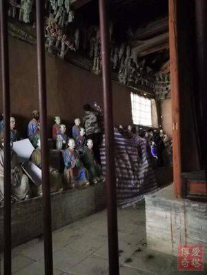 工作人员在给罗汉像盖塑料布，左边罗汉像间放着接水的器具，右下角地上也是漏雨的痕迹。图片来源：爱塔传奇公众号