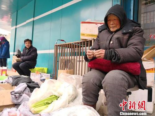 图为张菊芳老人正在卖菜。　甘芬 摄