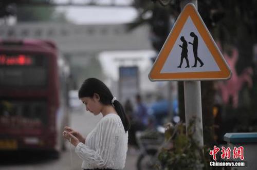资料图：市民过马路时仍在做“低头族”。陈超 摄