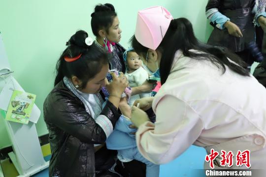 图为村民正在抱着孩子接种。　瞿宏伦 摄