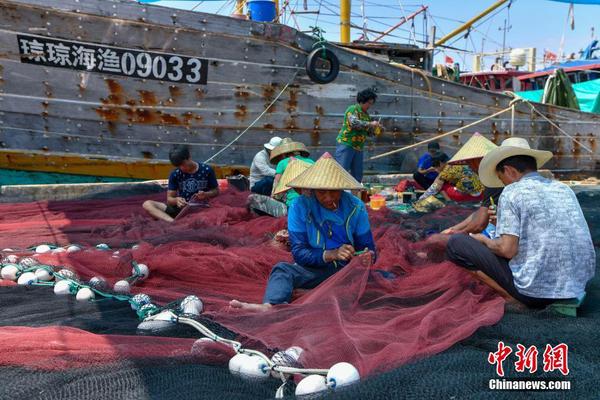 图为海南省琼海市潭门中心渔港的渔民正在修补渔网。
