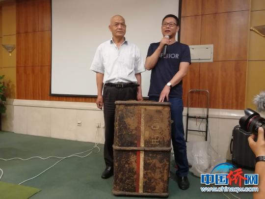 图为一战华工鞠星垣的第三代后裔鞠法全(左一)、第四代后裔鞠孝兵，在展示鞠星垣从英国带过来的一个箱子。　孙婷婷 摄