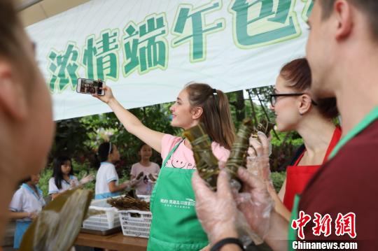 外国女性尤利娅用手机拍摄包粽子的场景 李星凯 摄