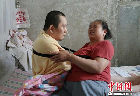 身体日渐衰老的梁青兰每次帮儿子翻身、坐立，全身的衣物都要湿透一次。　尚明侠 摄