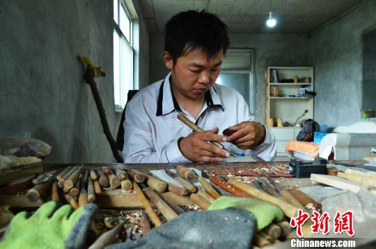 图为王吉涛在雕刻平安四季豆。　郝学娟 摄