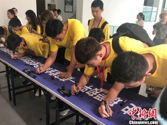 图为营员在和平寄语横幅上签名。杨颜慈 摄