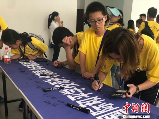 图为营员在和平寄语横幅上签名。杨颜慈 摄