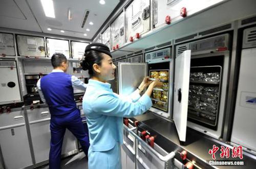 资料图：空乘在飞机上整理烤箱内的食物。 王东明 摄