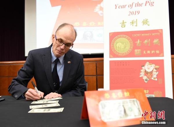 图为造币和印钞局局长莱昂纳德·奥利亚（Leonard R. Olijar）为民众在“吉利钱”上签名。