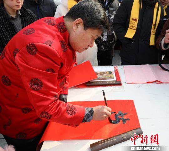 “与国咸休安富尊荣公府第，同天并老文章道德圣人家”，在孔府大门西侧，孔子第七十五代孙、孔子书画院名誉院长孔祥胜现场挥毫泼墨，孔府大门春联一气呵成。　孙广哲　摄