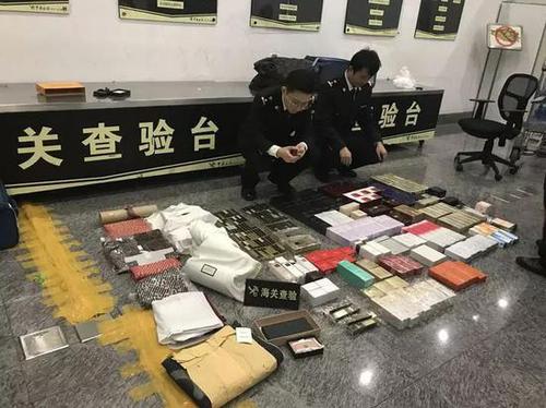 海关关员清点查获的超量奢侈品、护肤品