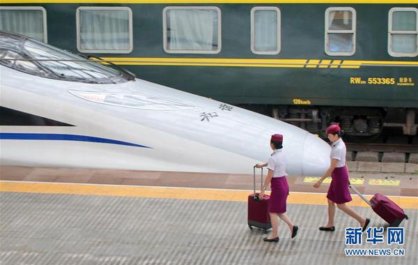 7月9日，在山东烟台火车站，两名列车员准备出乘。新华社发（唐克摄）