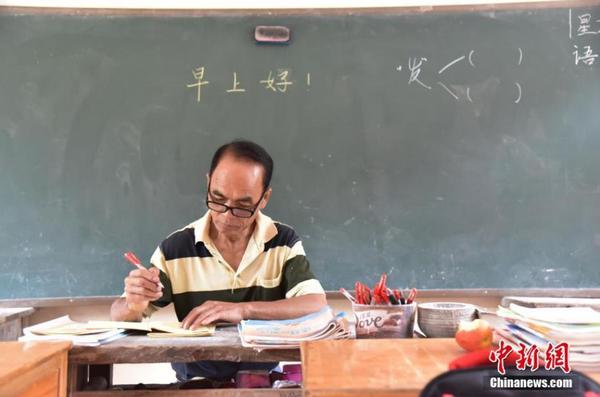 9月9日，62岁的周宏军，为广西柳州市融水苗族自治县汪洞乡达佑屯教学点学生上课。这是他坚守山区的第46年。图为周宏军在上课前批改学生的作业。王以照 摄