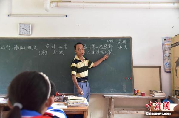 达佑屯地处九万大山腹地，曾一度不通公路，只得依靠周宏军用一根扁担徒步前往40公里远的乡政府挑运学习物品。图为周宏军在课堂上讲授古诗，他的教学成绩每年都在全乡教学点中名列前茅。林馨 摄