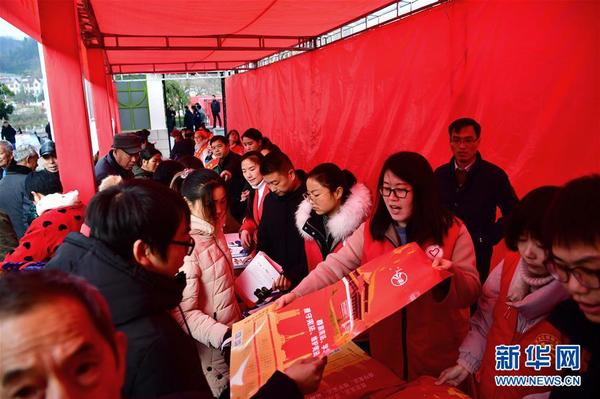 2 12月20日，在河南省信阳市新县举行的文化科技卫生“三下乡”集中示范活动现场，志愿者为群众发放挂历。  新华社记者冯大鹏摄