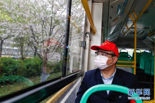 　3月25日，在武昌火车站综合体站始发的首趟518路公交车上，安全员熊伟望着窗外路边的樱花。 当日起，武汉市部分公交车恢复开行。 新华社记者 沈伯韩 摄