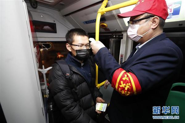 3月25日，在武昌火车站综合体站始发的首趟518路公交车上，安全员给乘客测量体温。 当日起，武汉市部分公交车恢复开行。 新华社记者 沈伯韩 摄