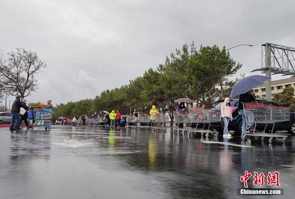 当地时间3月28日，美国旧金山湾区民众在位于福斯特城的Costco超市外冒雨排起长队，等候购买物资。中新社记者 刘关关 摄