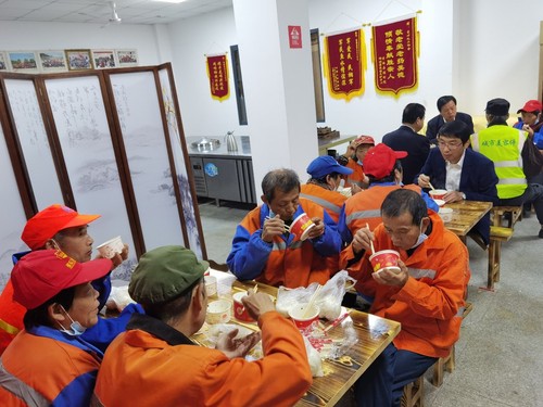 图为县领导陪环卫工人一起吃早餐