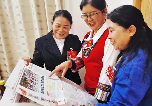 住滇全国政协委员黄丽云、丁秀花、资艳萍（从左至右）阅读人民政协报，就更好的培养孩子们成为新时代接班人等教育问题各抒己见。 特邀委员记者 茸芭莘那 摄