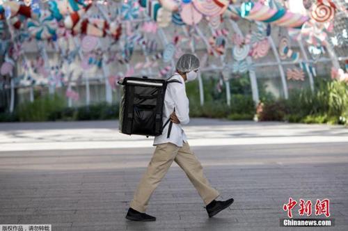 资料图：当地时间2021年1月4日，泰国曼谷，一名快递员“全副武装”走在街头。